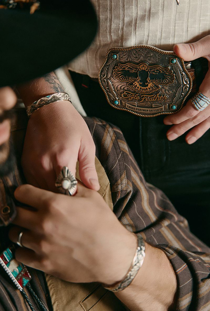Close-up of rings, bracelets, and a western belt buckle from Ian Munsick’s jewelry collection