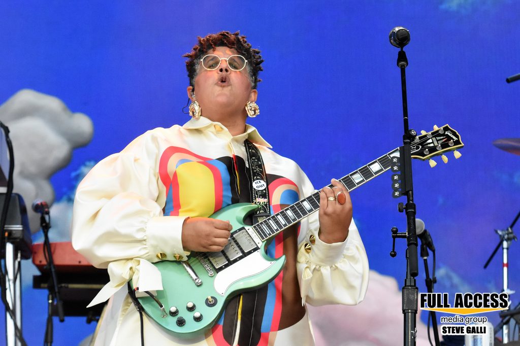 Guitarist in a colorful jacket playing a mint-green electric guitar