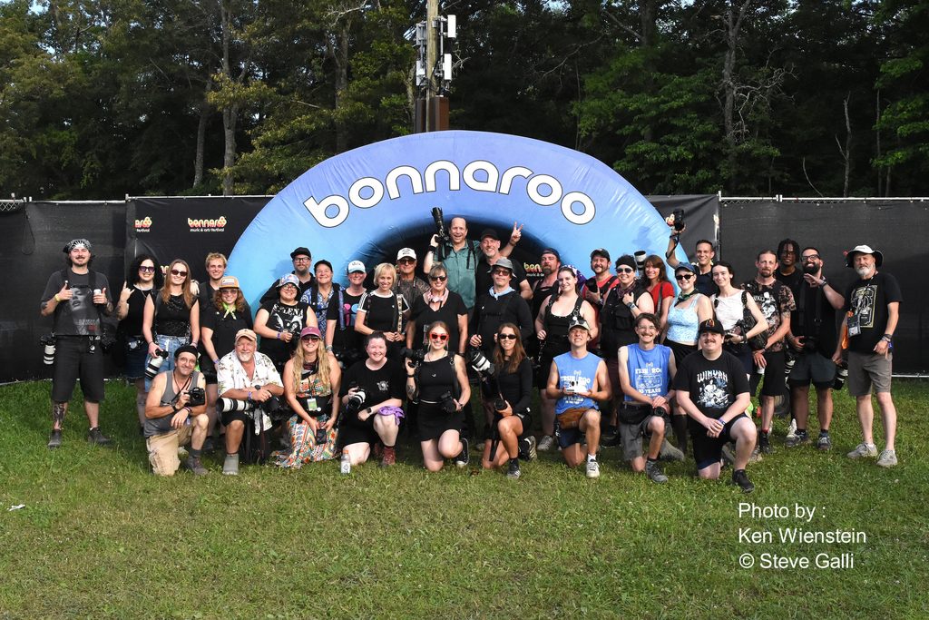 Group photograph in front of a blue Bonnaroo sign
