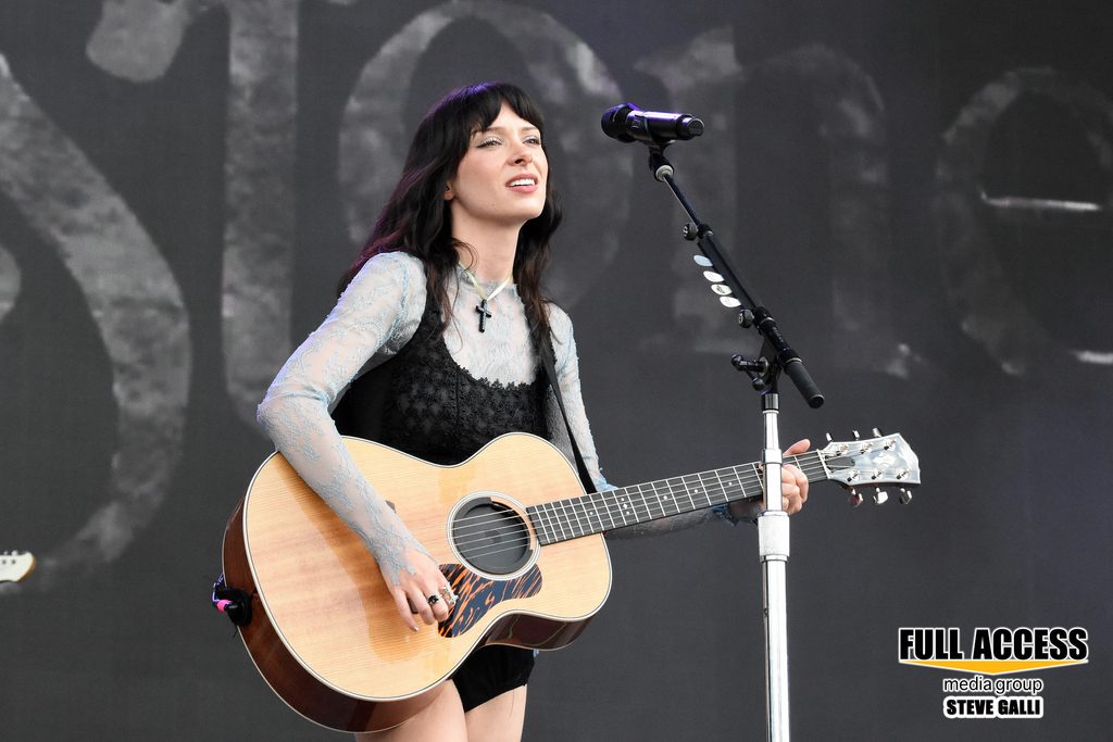 Singer playing an acoustic guitar at a microphone on the Bonnaroo stage