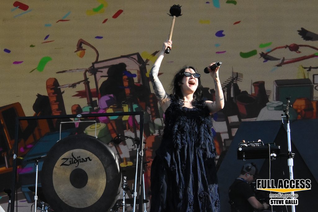Singer in a black dress raising a microphone beneath falling confetti