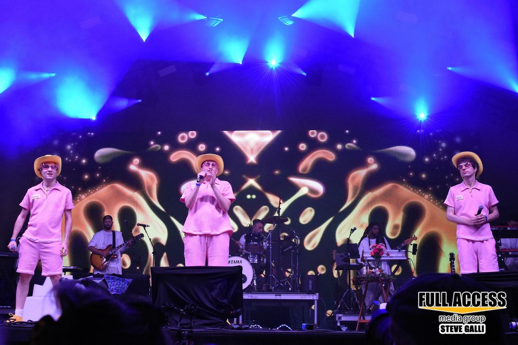 Three performers in matching pink outfits and cowboy hats on stage