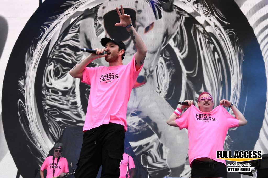 Two performers in matching pink shirts addressing the festival crowd