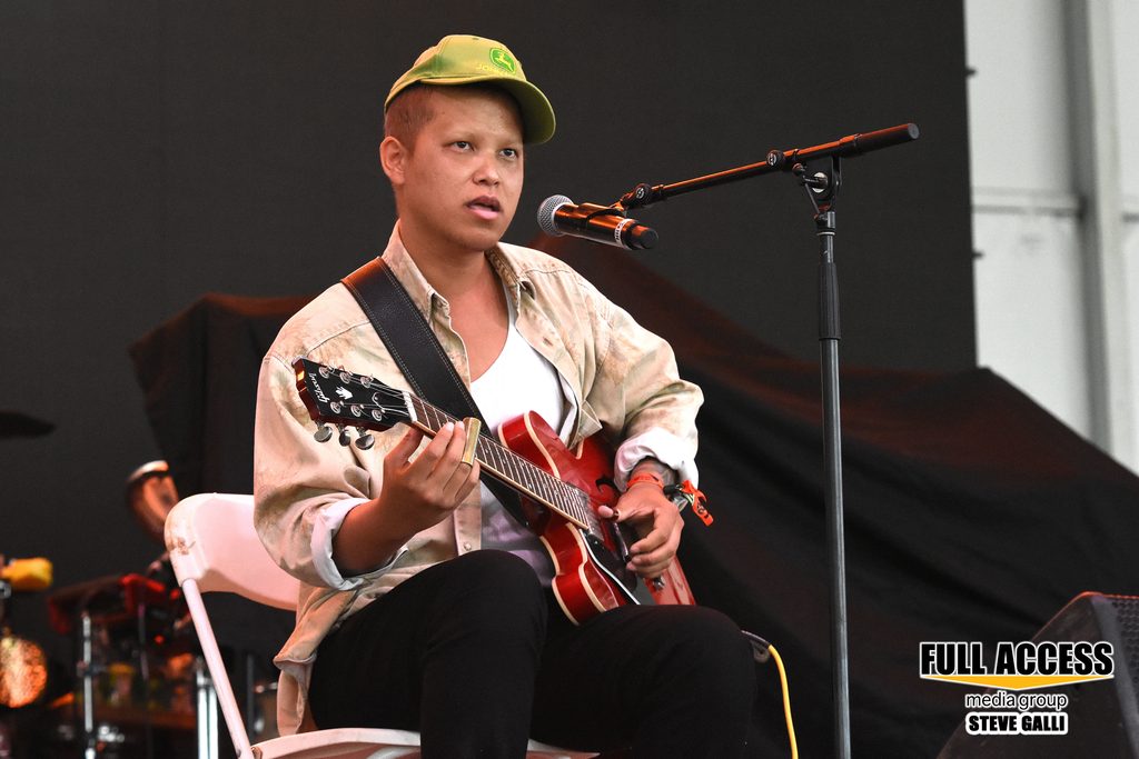 Seated guitarist singing into a microphone at Bonnaroo
