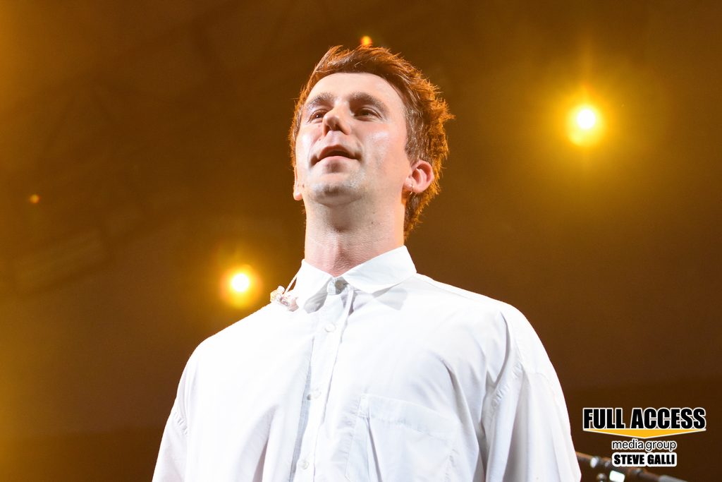 Performer in a buttoned white shirt under warm stage lighting