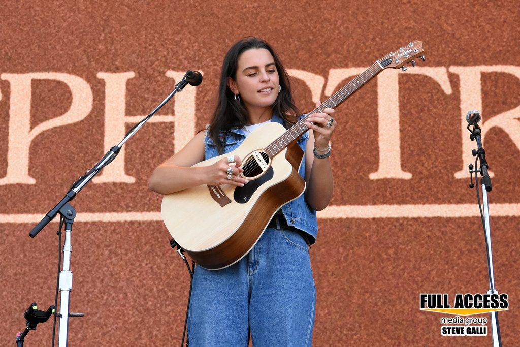 Musician in a blue outfit playing an acoustic guitar