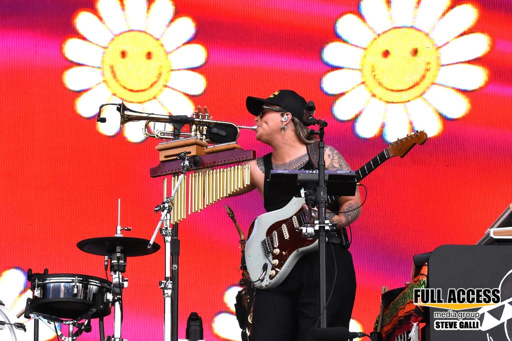 Musician playing a trumpet while wearing an electric guitar