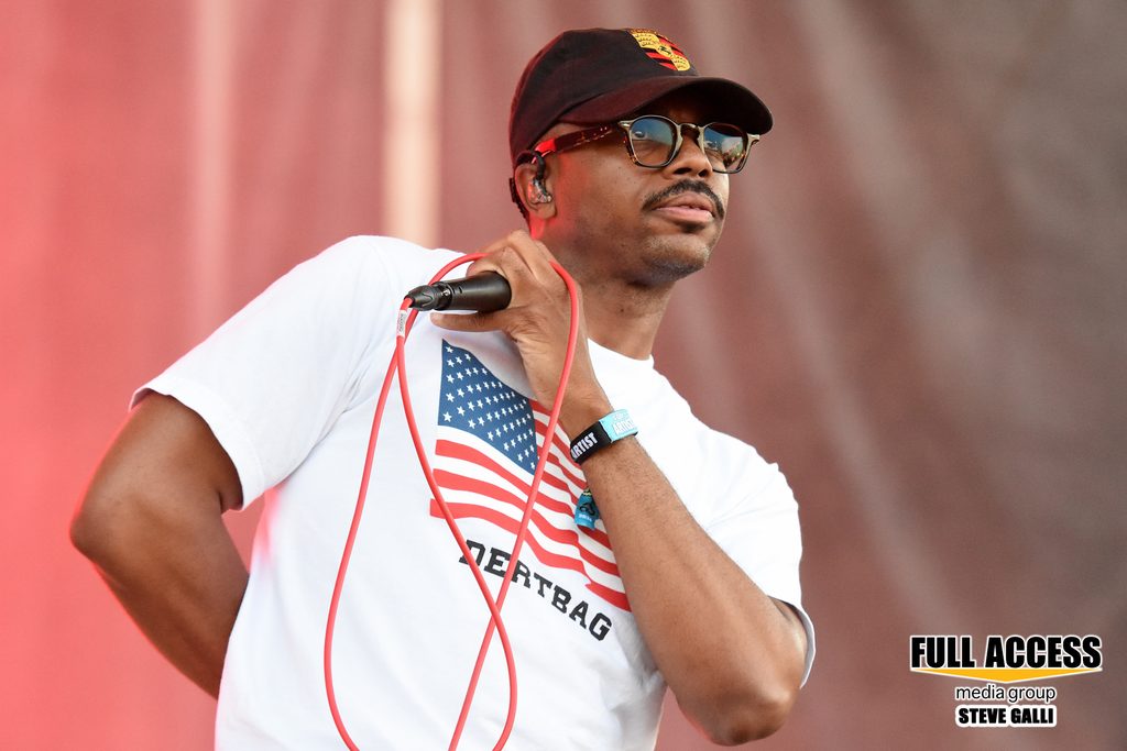 Vocalist in sunglasses holding a microphone with a red cable