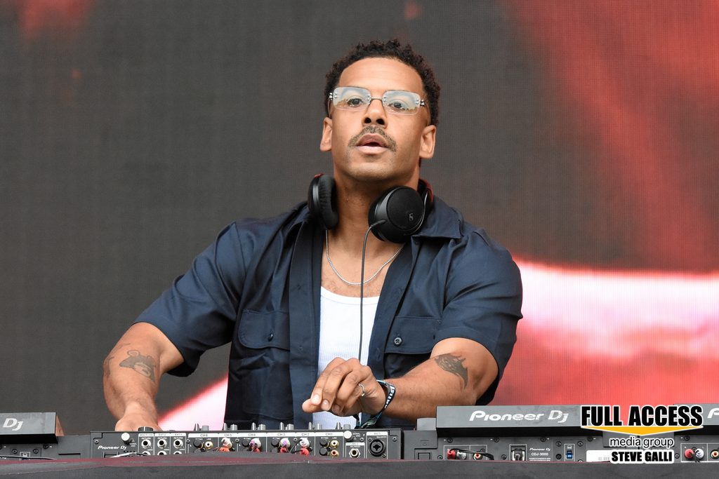 DJ working at a mixing console with headphones around his neck