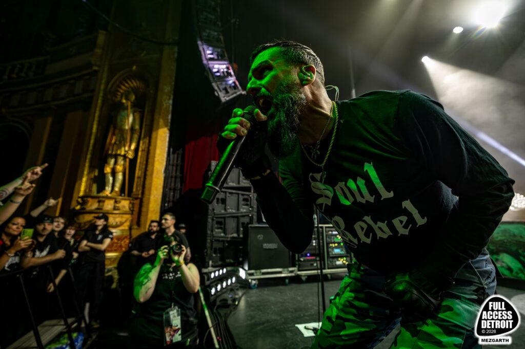 Vocalist leaning toward the audience at the front of the Fillmore stage