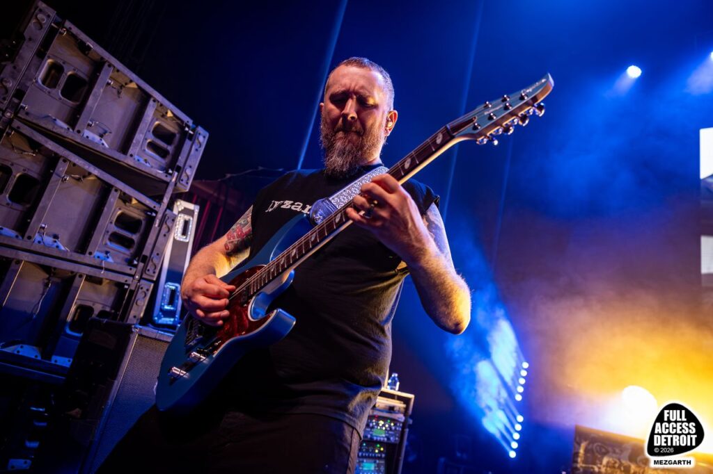 Low-angle view of a guitarist playing under blue and yellow stage lights