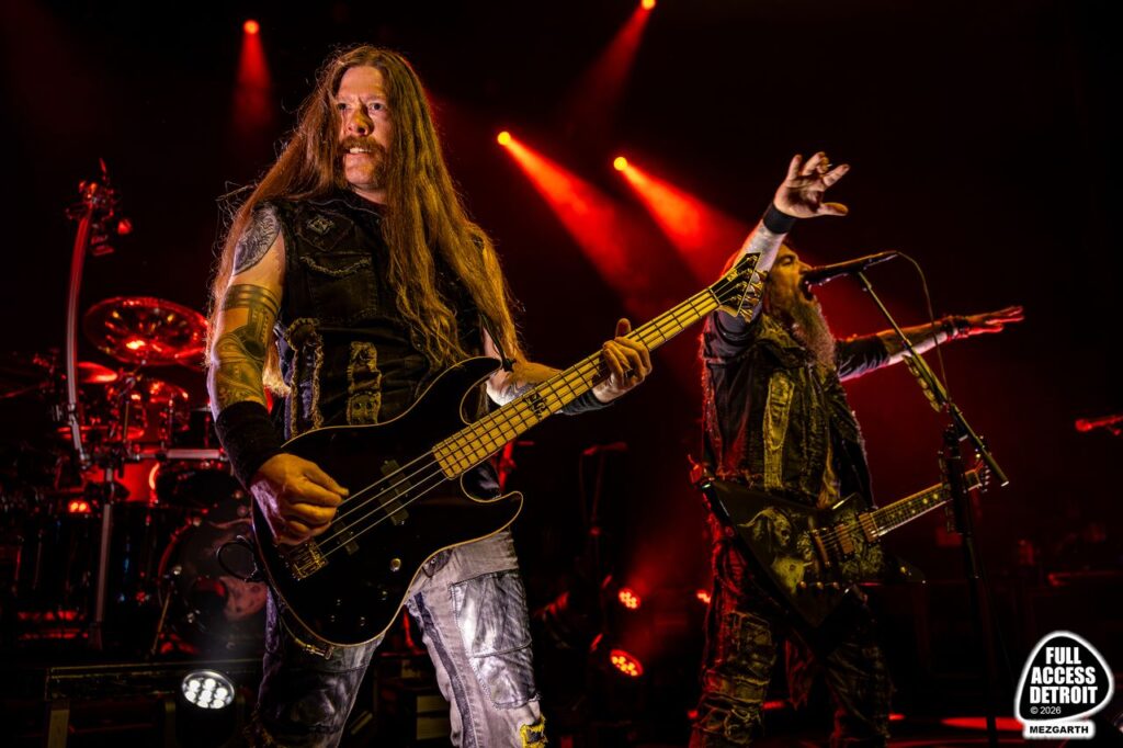 Bassist performing while another band member raises an arm behind him