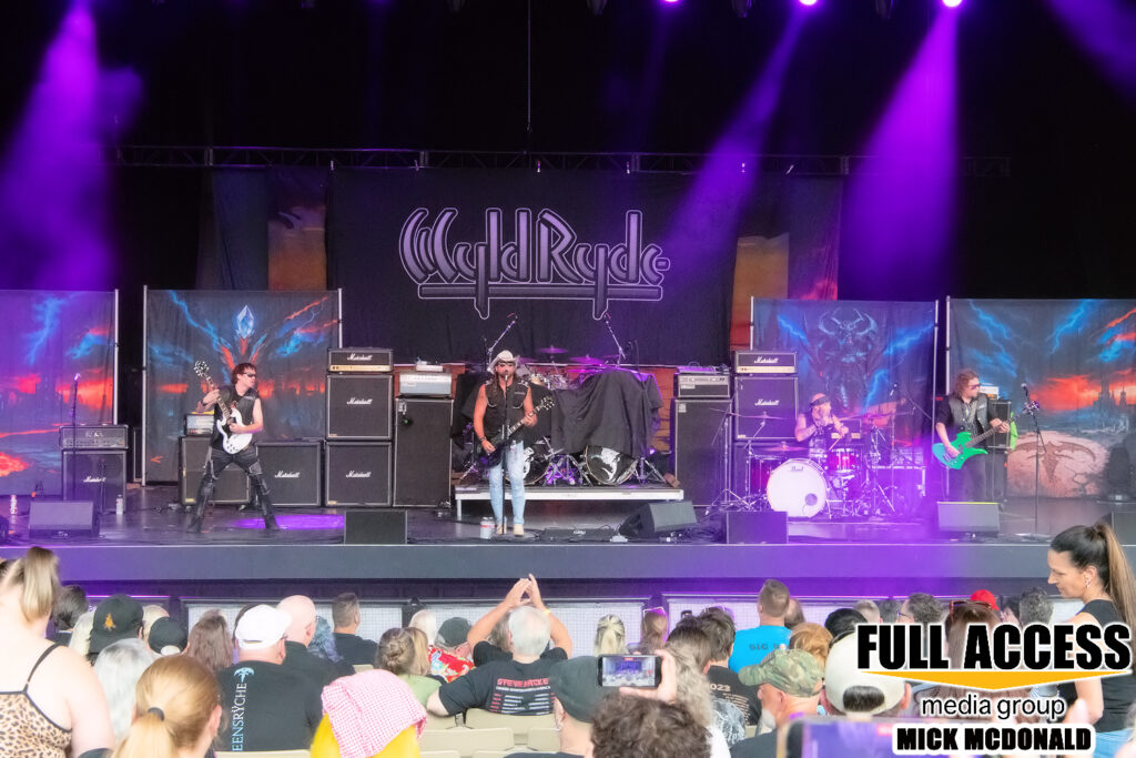 Wyld Ryde performing on the Iroquois Amphitheater stage under purple lights