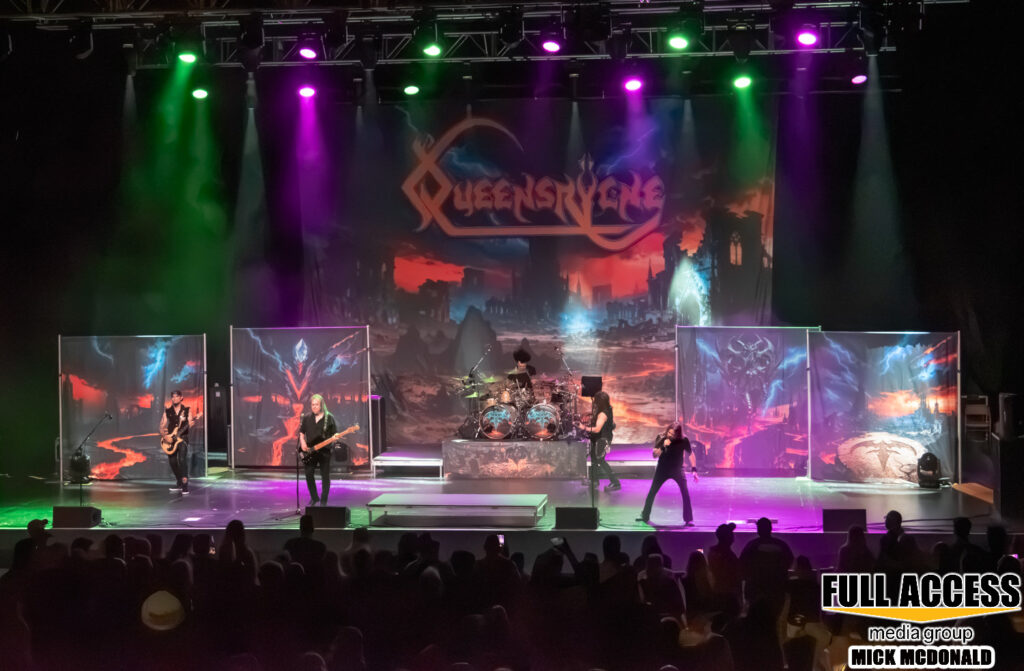 Wide view of Queensrÿche performing on the illuminated amphitheater stage