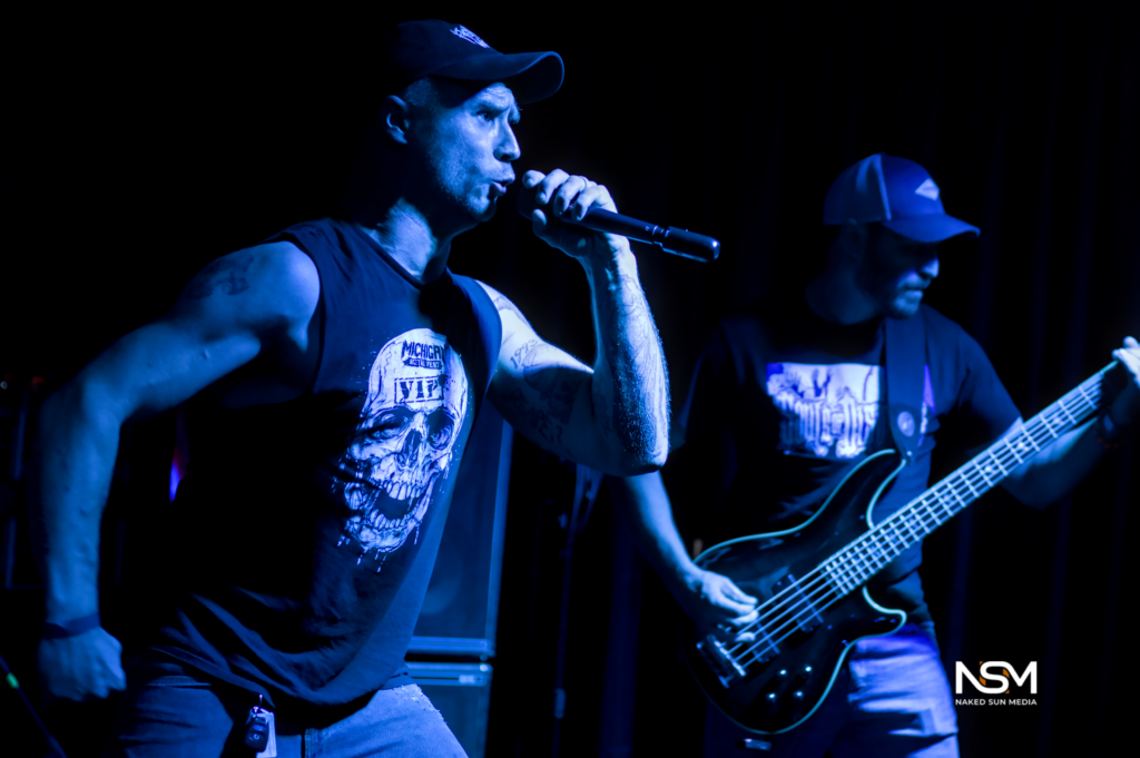 Vocalist and bassist performing under blue stage lights