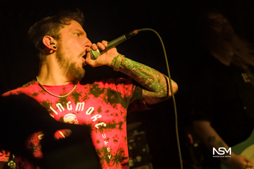 Vocalist in a red shirt holding a microphone