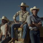 Midland band members in cowboy hats beside a yellow vehicle in the desert.