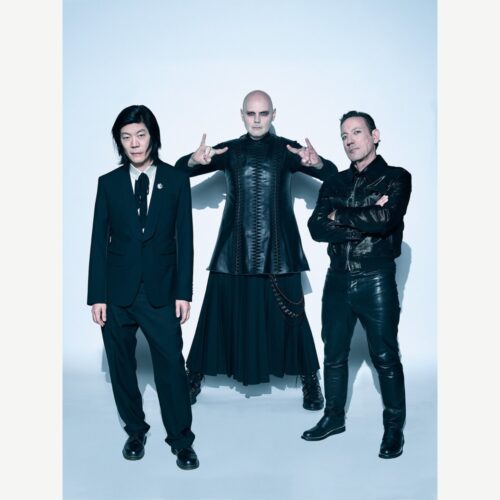 The Smashing Pumpkins posing together against a pale studio background.
