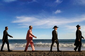 U2 band members walking together on a beach.