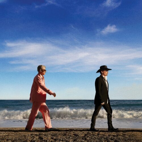 U2 band members walking together on a beach.